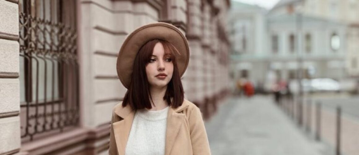 woman in wearing a brown coat walking on side walk